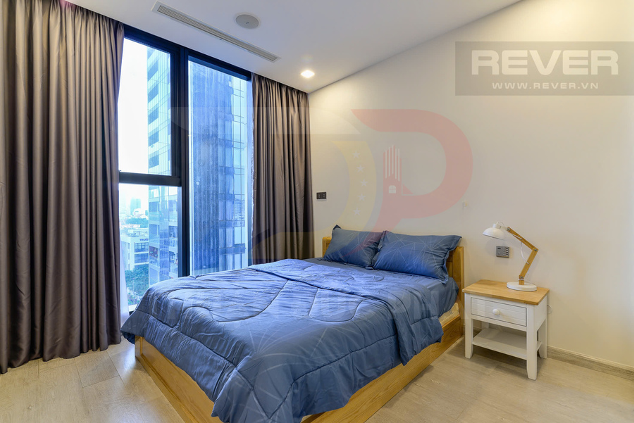 Phòng ngủ chung cư hiện đại với giường gỗ chăn ga xanh, cửa sổ kính lớn và bàn đầu giường có đèn ngủ