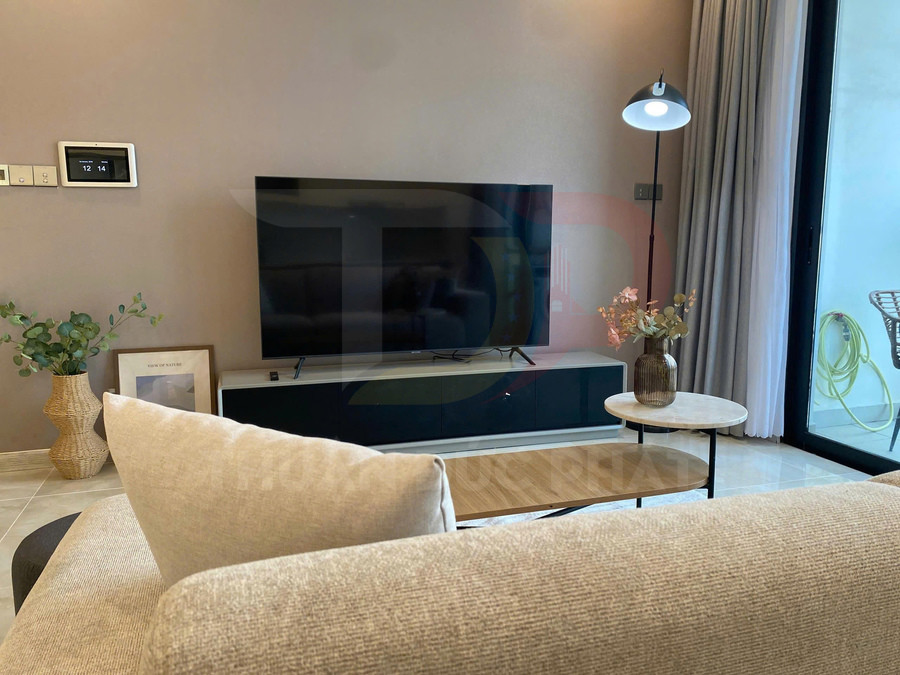 Tivi màn hình phẳng đặt trên kệ gỗ trong phòng khách hiện đại, phía trước là sofa và bàn trà nhỏ