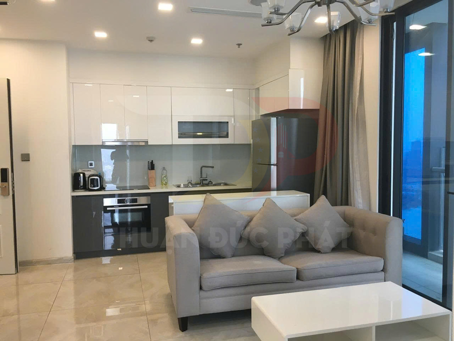 Phòng khách căn hộ với sofa xám, bàn trà trắng liền kề bếp nhỏ hiện đại và tủ lạnh inox