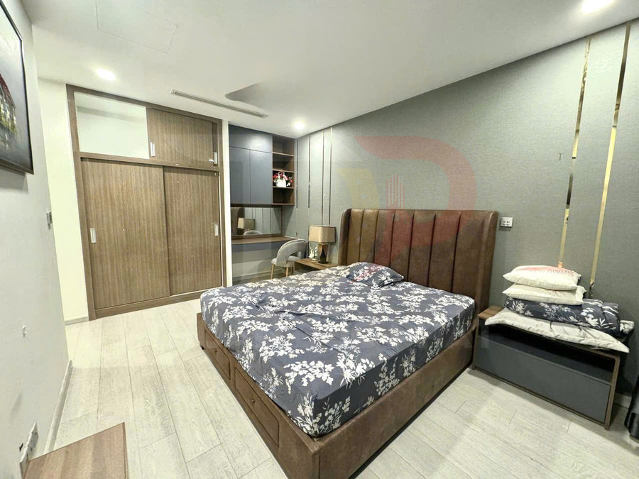 Phòng ngủ hiện đại với giường bọc da nâu, chăn ga hoa tối màu và tủ quần áo gỗ cửa lùa