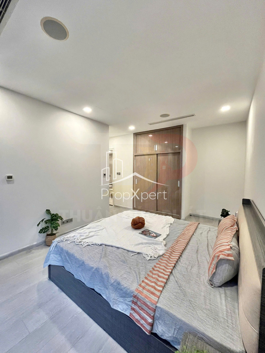 Phòng ngủ hiện đại với giường đôi trải ga xám, chăn kẻ sọc cam và tủ quần áo gỗ cửa trượt