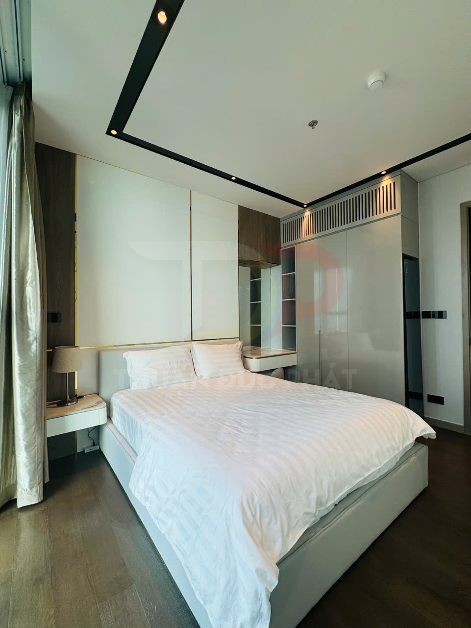 Phòng ngủ hiện đại với giường đôi bọc nệm trắng, tủ quần áo âm tường và cửa sổ lớn có rèm sáng màu