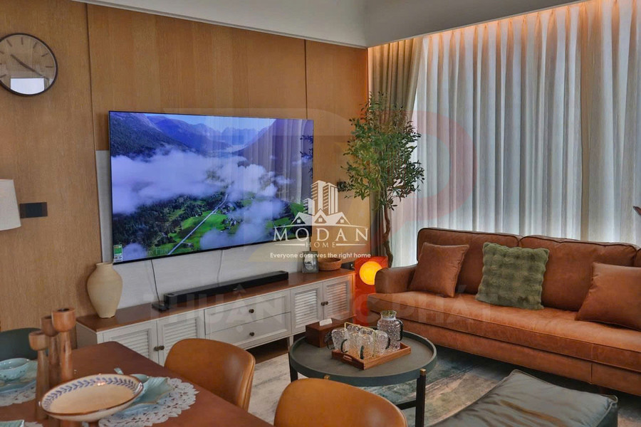 Phòng khách hiện đại với tivi màn hình phẳng treo tường, sofa da nâu và bàn trà trang trí gọn gàng