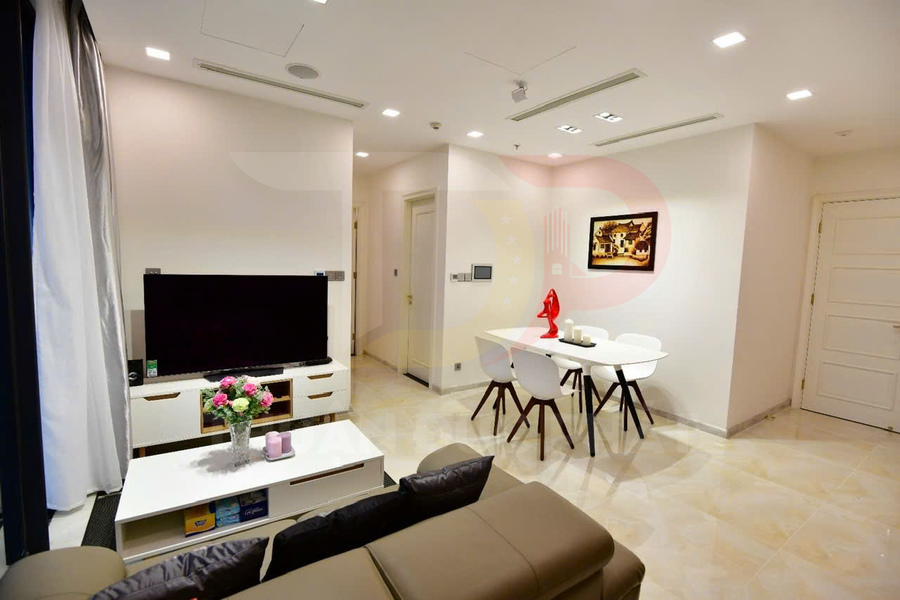 Phòng khách căn hộ hiện đại với tivi màn hình phẳng, bàn trà và bàn ăn nhỏ bốn ghế tông trắng sáng