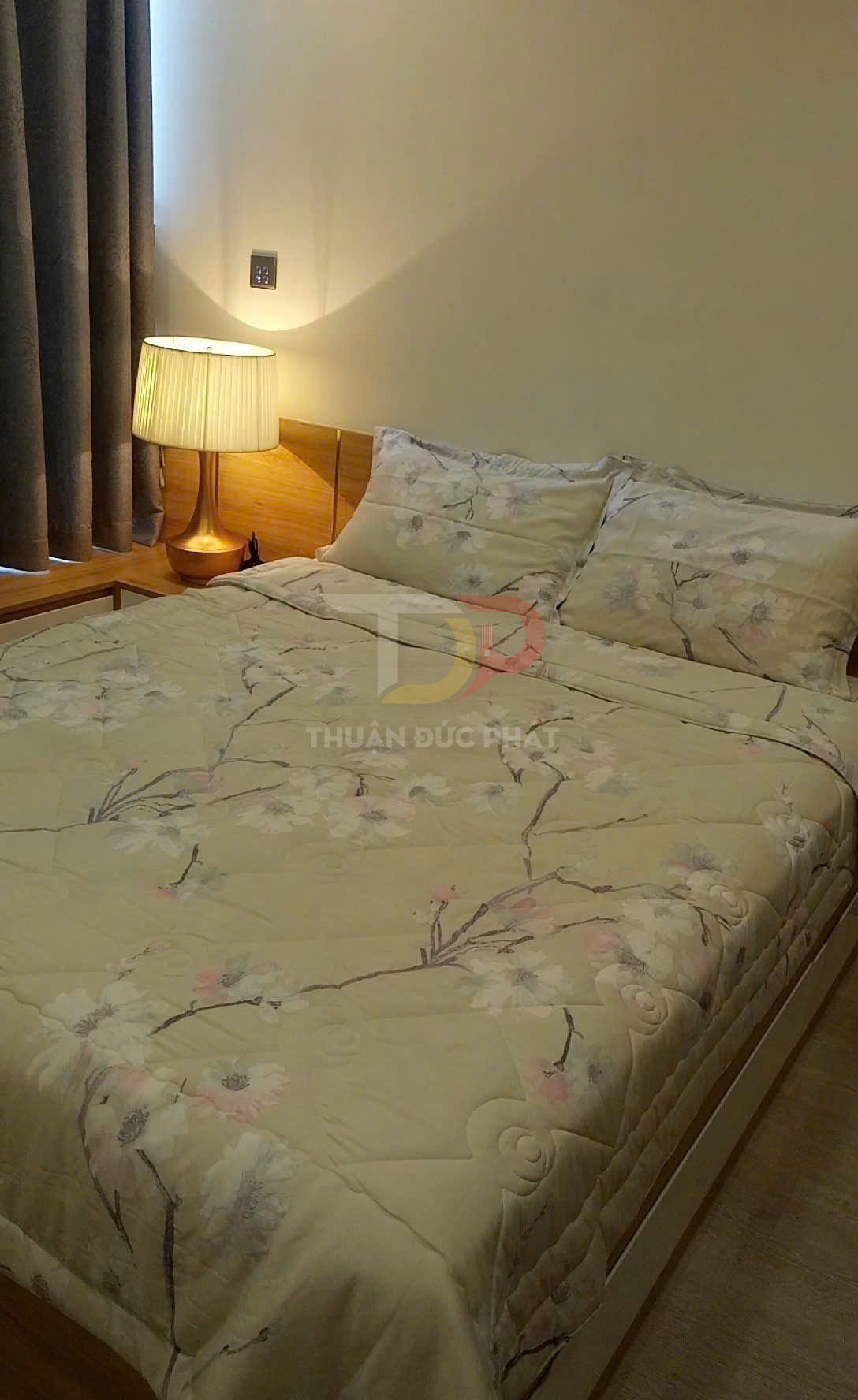 Bộ chăn ga gối hoa nhã nhặn trên giường gỗ cạnh đèn ngủ trong phòng ngủ ấm cúng