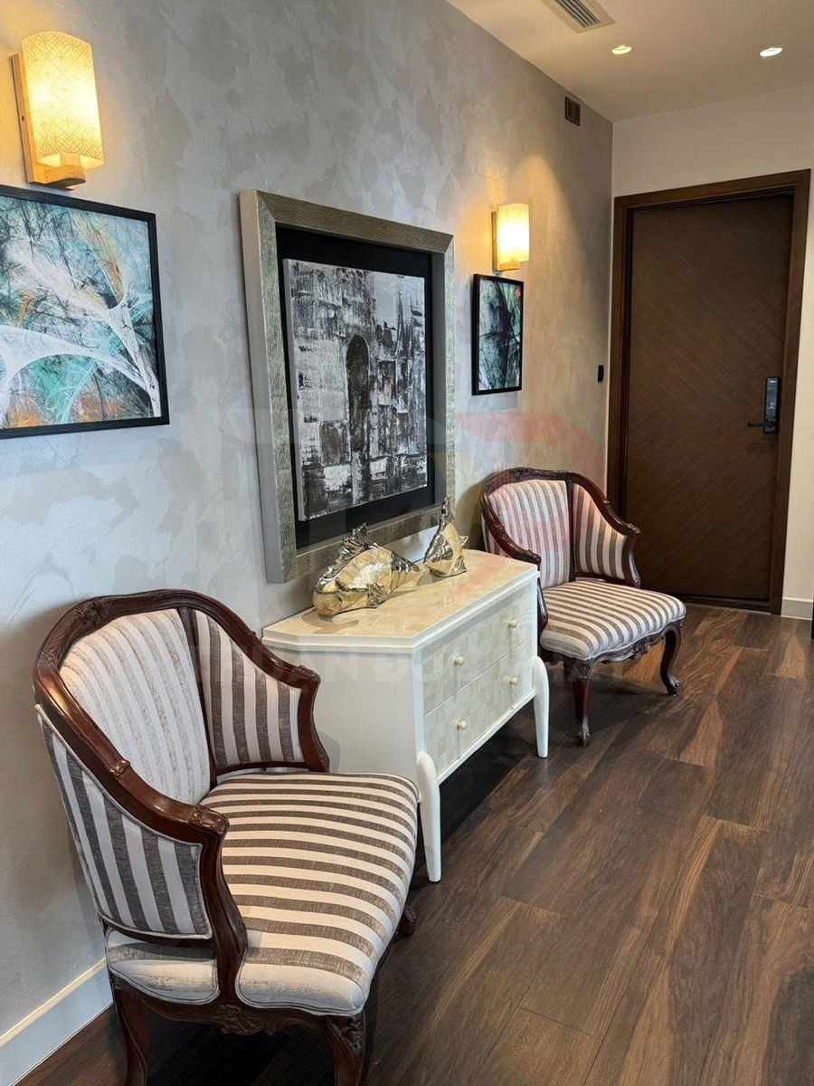 Hai ghế salon tân cổ điển bọc nệm sọc đặt cạnh tủ gỗ nhỏ trong hành lang sang trọng
