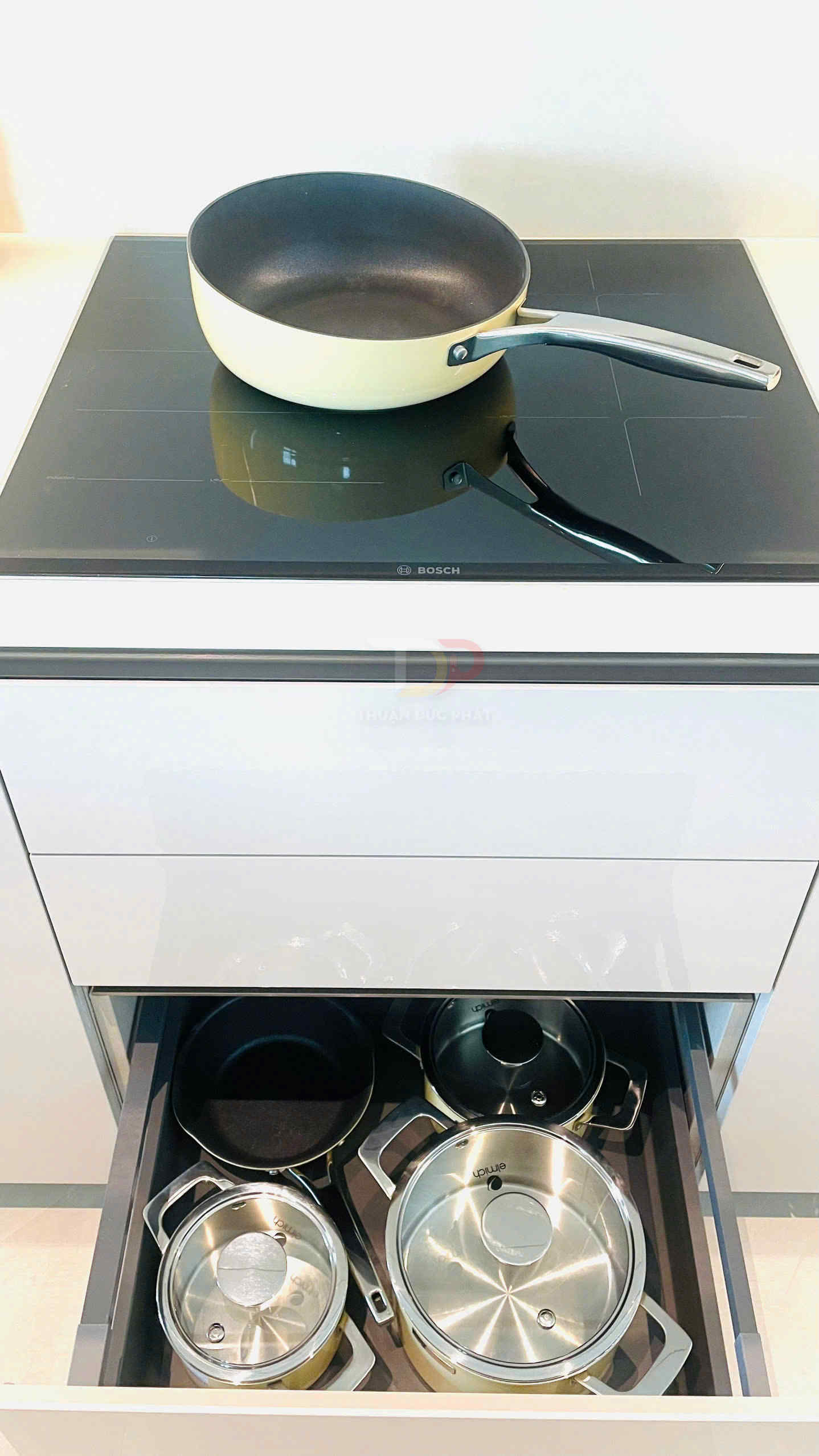 Bếp từ Bosch với chảo chống dính màu kem và ngăn kéo dưới đựng bộ nồi chảo inox
