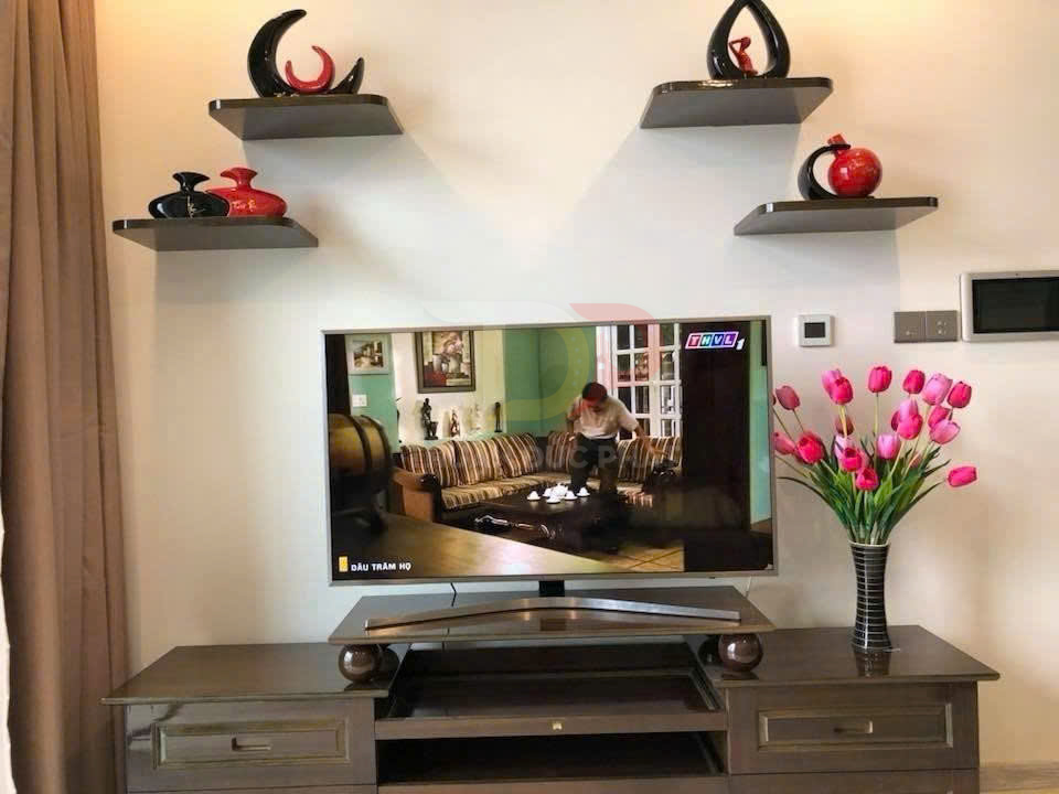 Kệ tivi gỗ hiện đại với tivi màn hình phẳng và bình hoa tulip hồng trang trí phòng khách