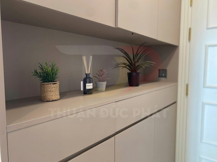 Tủ gỗ âm tường màu be trang trí chậu cây nhỏ và lọ tinh dầu khuếch tán hương thơm