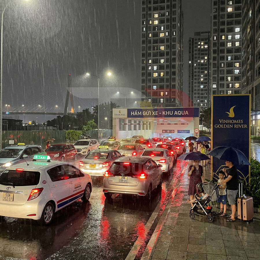 Ô tô xếp hàng dài trước hầm gửi xe Vinhomes Golden River trong trời mưa ban đêm
