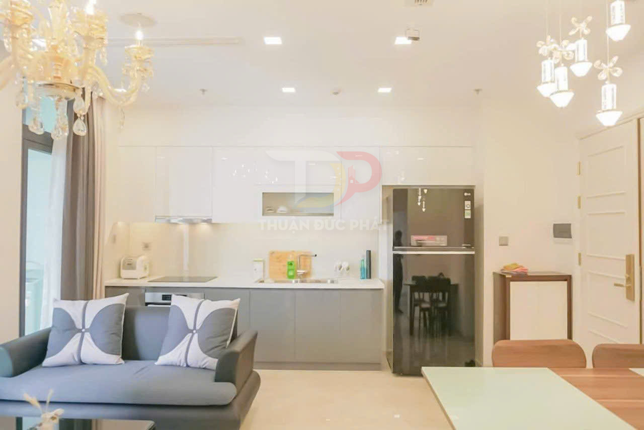 Phòng bếp hiện đại với tủ bếp trắng xám, sofa xám và tủ lạnh hai cửa màu đen sáng bóng
