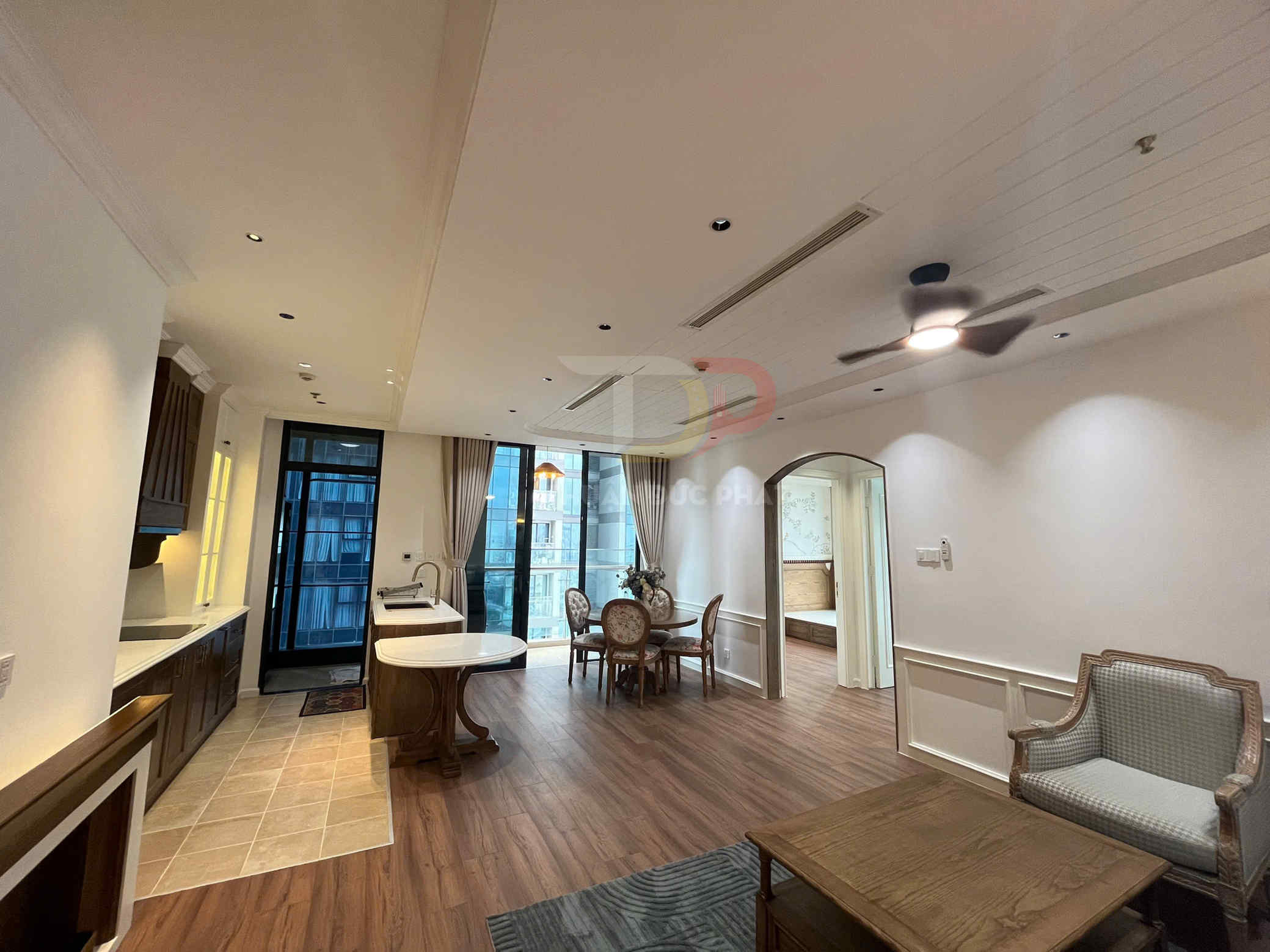 Phòng khách liền bếp chung cư nội thất gỗ cao cấp với bàn ăn, ghế sofa và trần quạt trần hiện đại