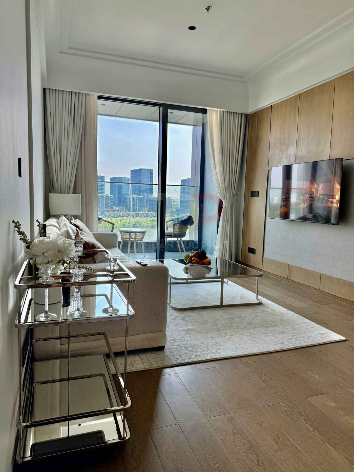 Phòng khách chung cư hiện đại với sofa trắng, bàn trà kính, kệ trang trí và cửa kính lớn nhìn ra thành phố