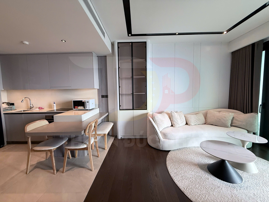 Phòng khách căn hộ hiện đại với sofa cong màu kem, bàn trà tròn và bếp liền kề có bàn ăn gỗ