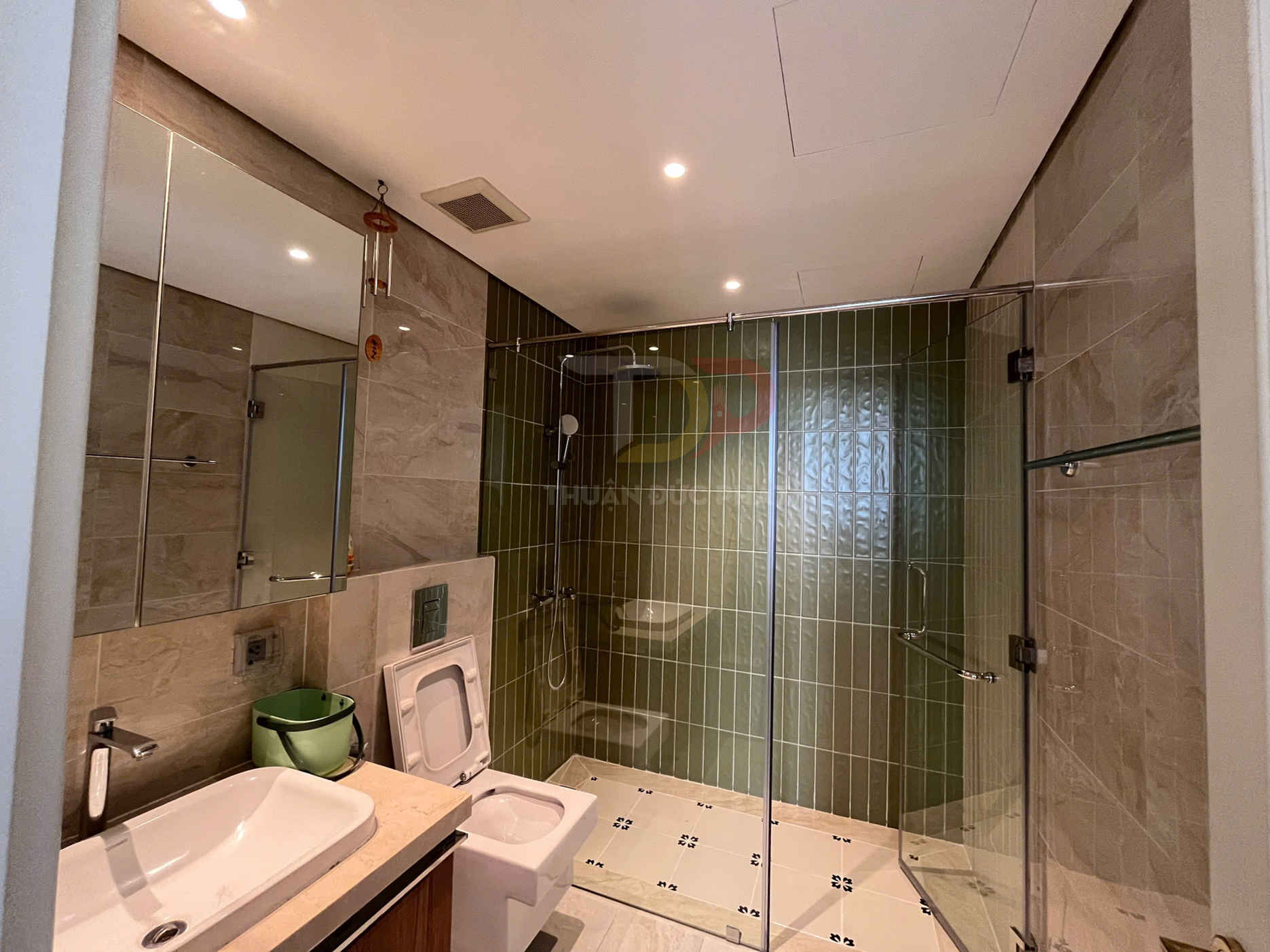 Phòng tắm hiện đại với bồn rửa, bồn cầu và buồng tắm kính vách gạch xanh