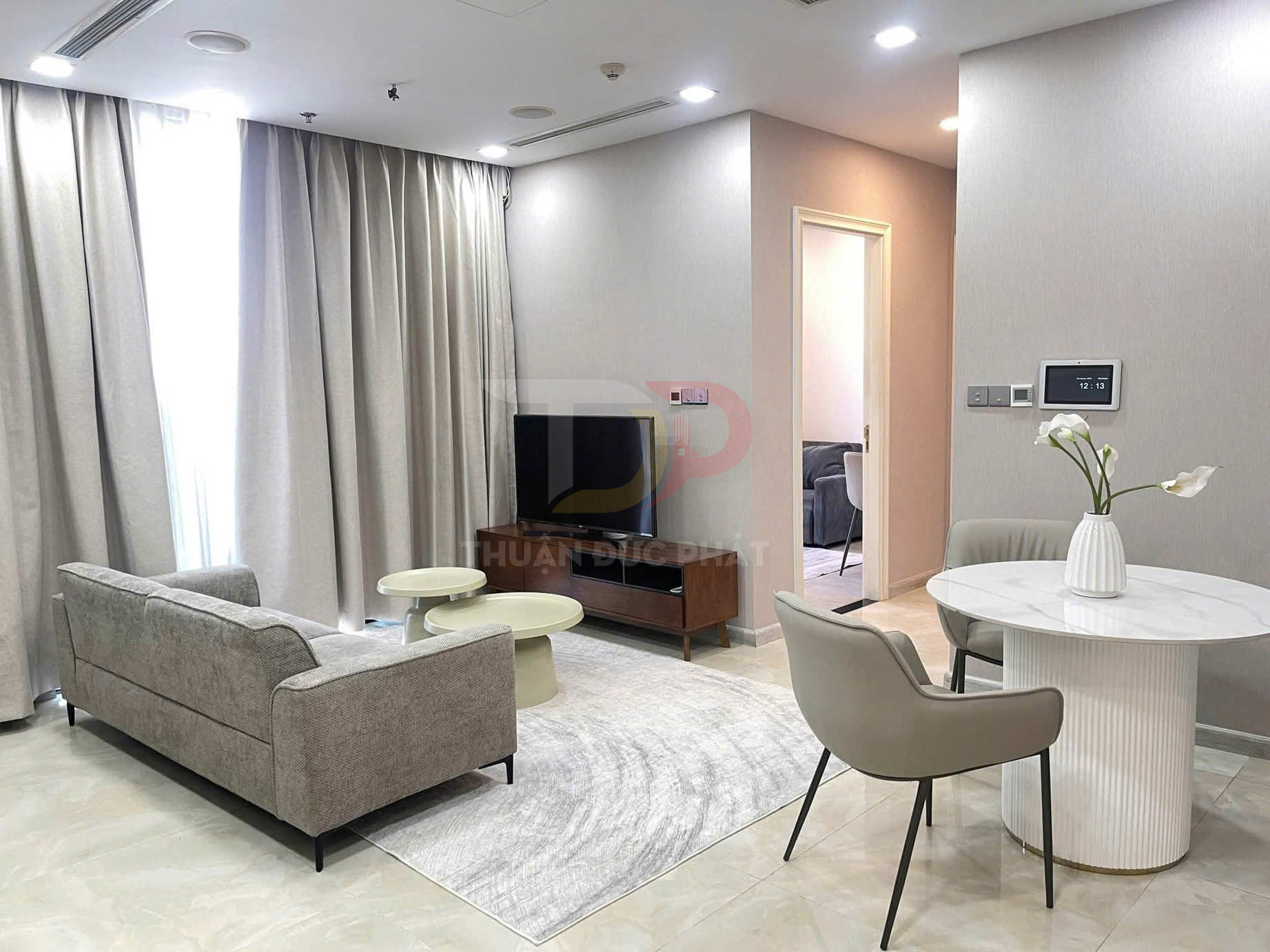 Phòng khách chung cư hiện đại với sofa xám, bàn trà, bàn ăn tròn và rèm cửa cao cấp màu sáng