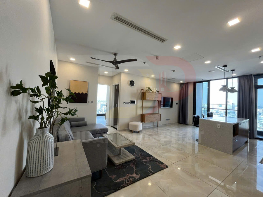 Phòng khách căn hộ hiện đại với sofa xám, bàn kính, kệ gỗ treo tường và bếp mở cạnh cửa sổ lớn view thành phố