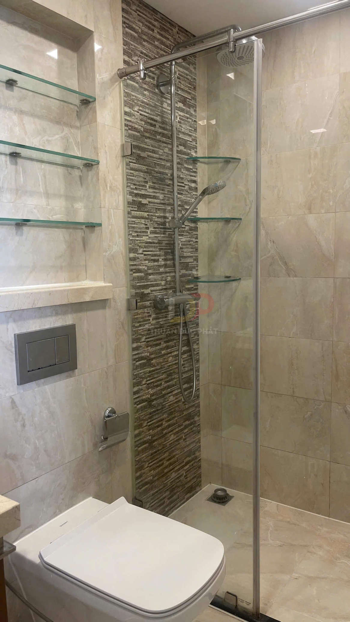Phòng tắm hiện đại với bồn cầu treo tường, vách kính tắm đứng và vòi sen inox kèm kệ kính