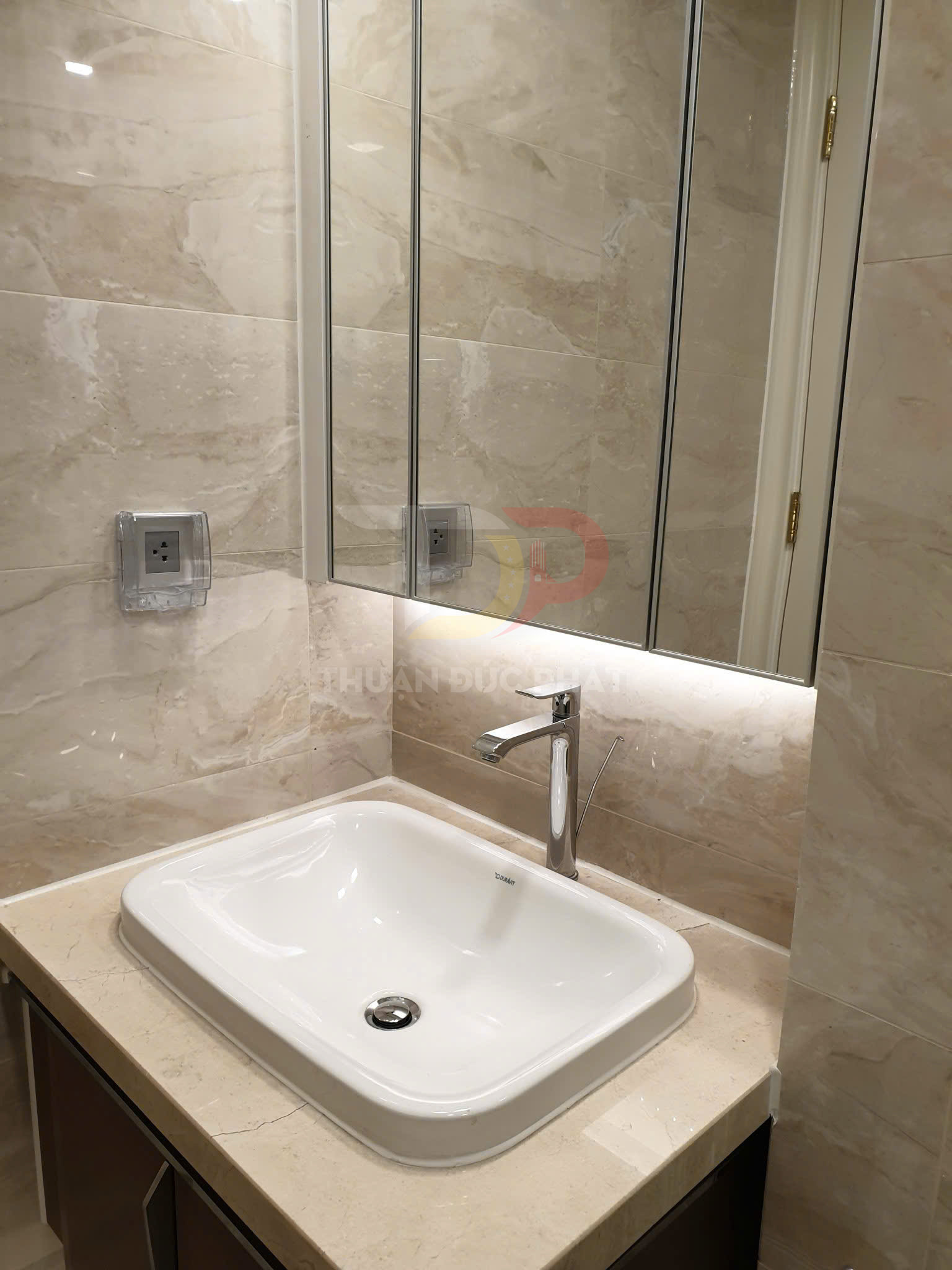 Chậu rửa mặt đặt bàn màu trắng với vòi nước inox hiện đại trên mặt đá marble trong phòng tắm sáng sạch