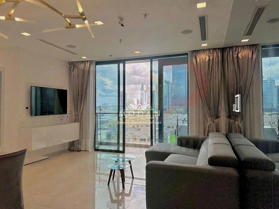 Phòng khách căn hộ cao cấp với sofa xám, bàn kính nhỏ và cửa kính lớn nhìn ra thành phố