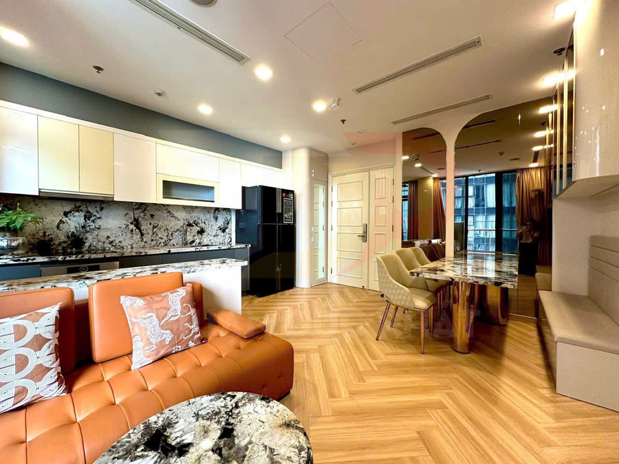 Phòng bếp và phòng ăn chung cư hiện đại với tủ bếp trắng, sofa da cam và bàn ăn mặt đá sang trọng