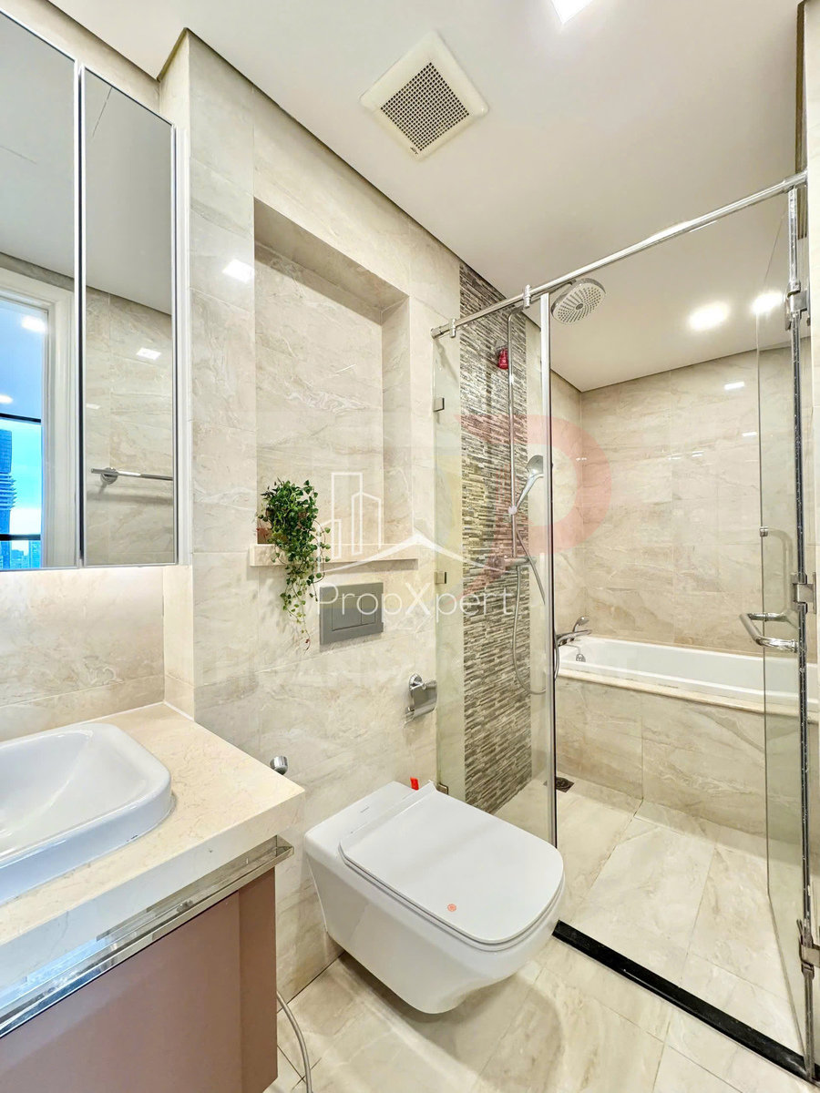 Phòng tắm hiện đại với bồn cầu treo tường, buồng tắm kính, bồn tắm nằm và lavabo mặt đá sáng màu