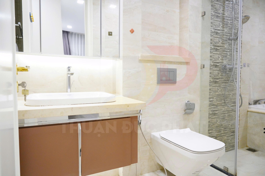 Phòng tắm hiện đại với bồn rửa mặt, bồn cầu treo tường và khu vực tắm kính sang trọng