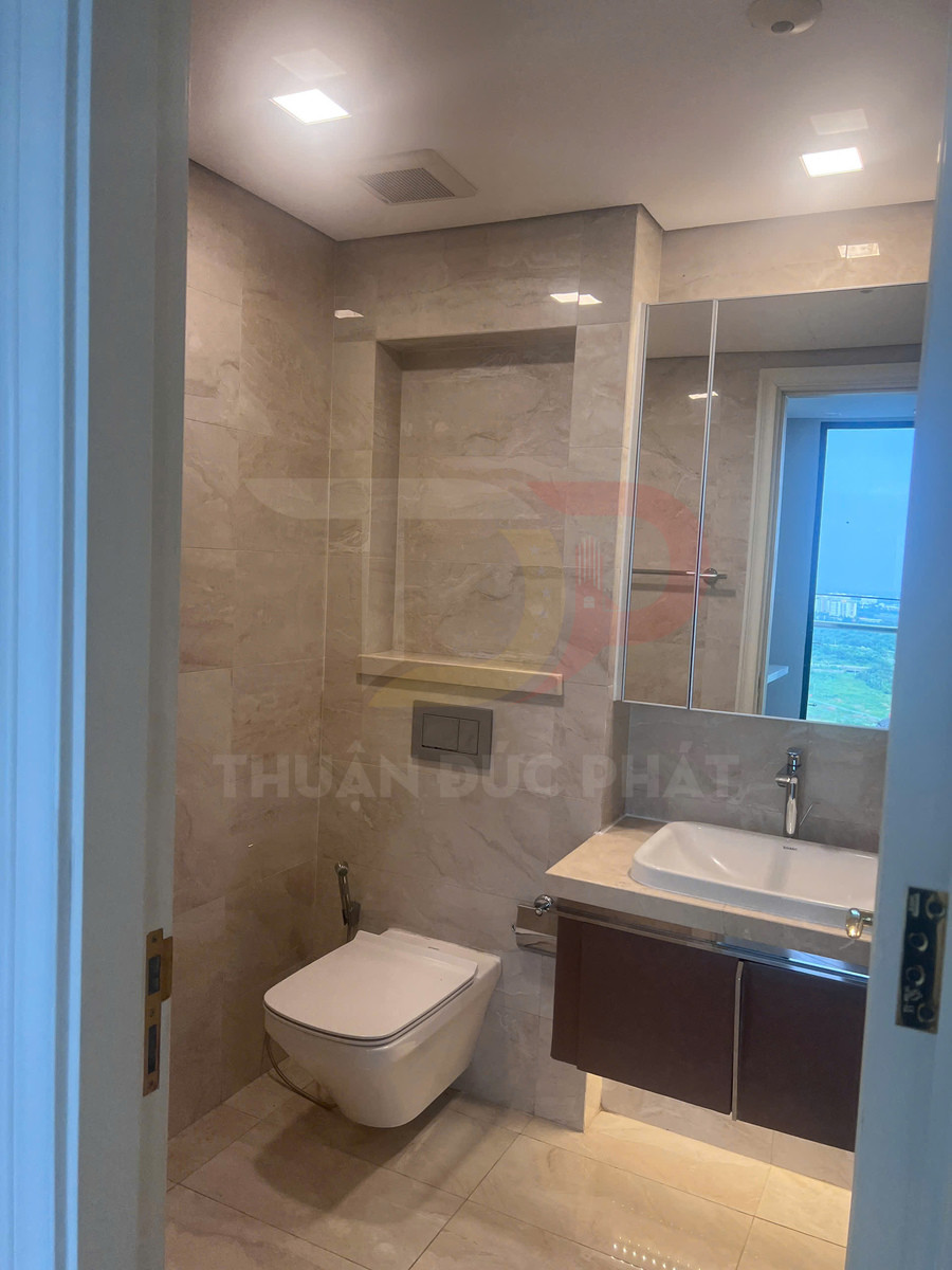Phòng tắm hiện đại với bồn cầu treo tường, lavabo đá và tủ gỗ dưới gương lớn