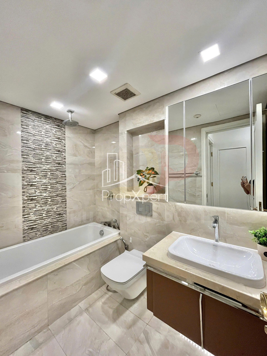 Phòng tắm hiện đại với bồn tắm nằm, bồn cầu treo tường và lavabo đặt trên tủ gỗ sang trọng