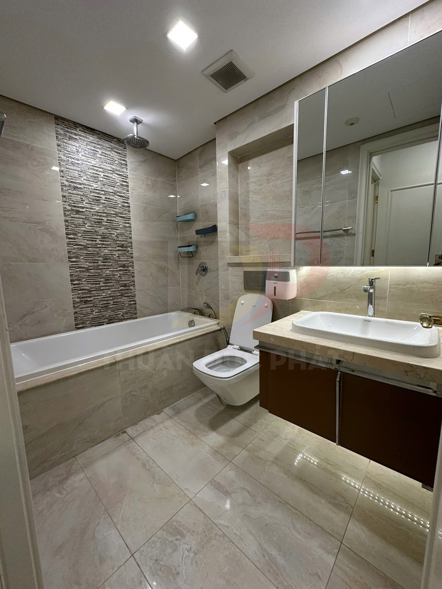 Phòng tắm hiện đại với bồn tắm nằm, bồn cầu, lavabo đá và tủ gương treo tường sáng đèn