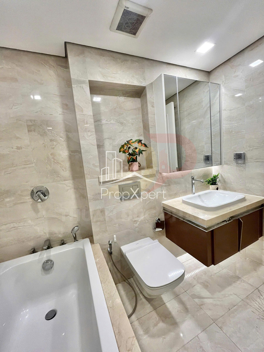 Phòng tắm hiện đại với bồn tắm, bồn cầu thông minh, lavabo đá và tủ gỗ treo tường