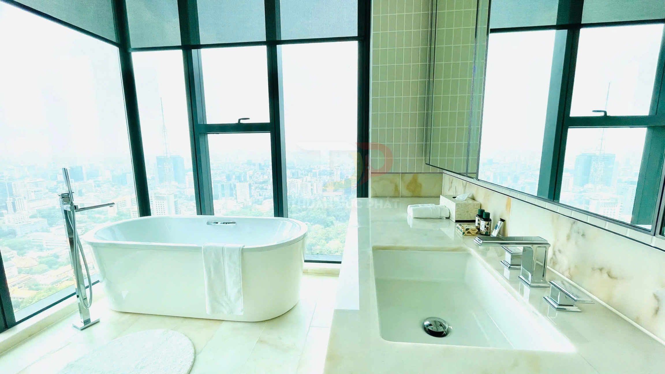Bồn tắm đứng độc lập cạnh cửa kính lớn và bồn rửa mặt đá cẩm thạch trong phòng tắm hiện đại cao cấp