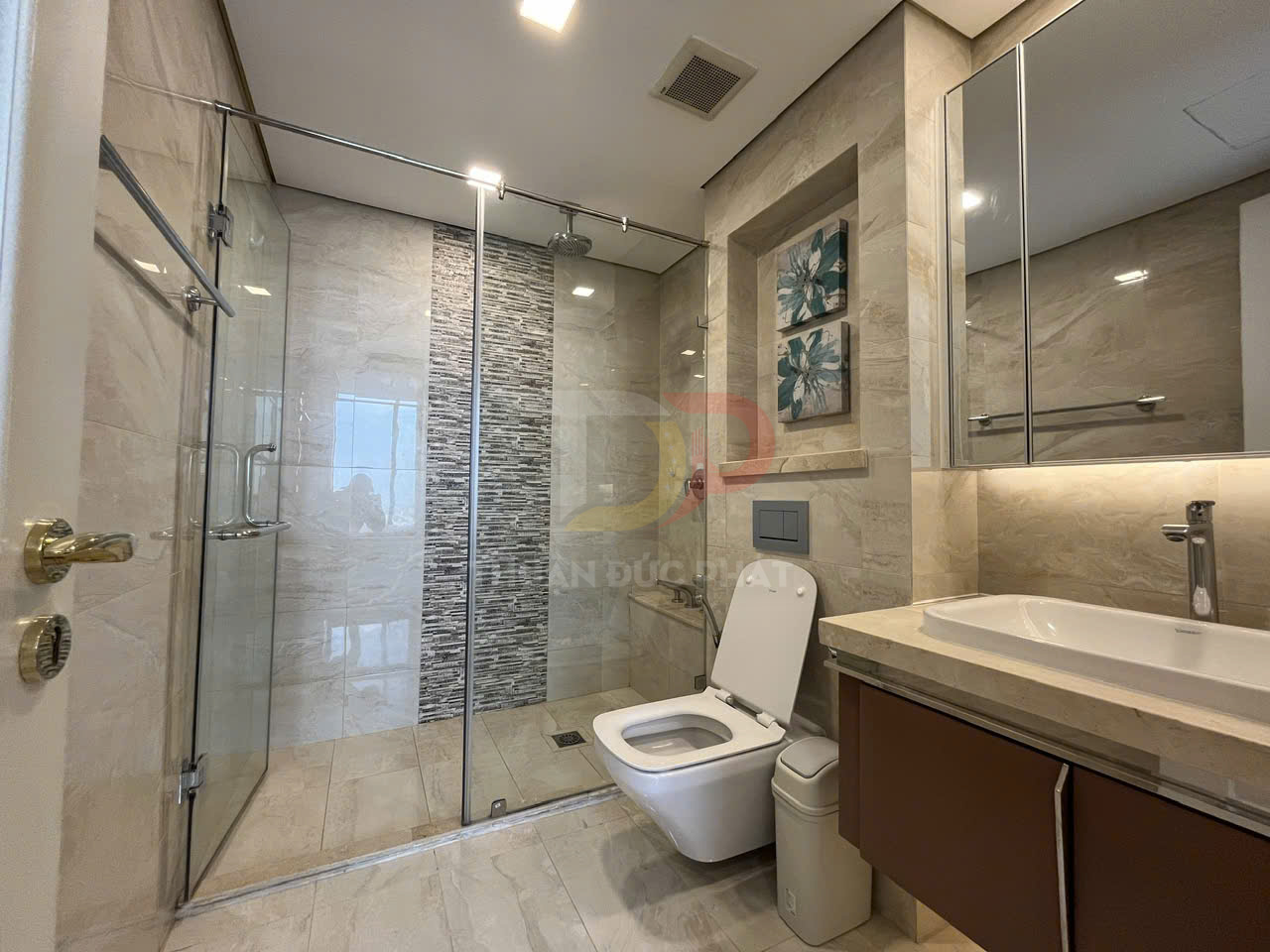 Phòng tắm hiện đại với buồng tắm kính, bồn cầu trắng và lavabo đá kèm tủ gỗ sang trọng