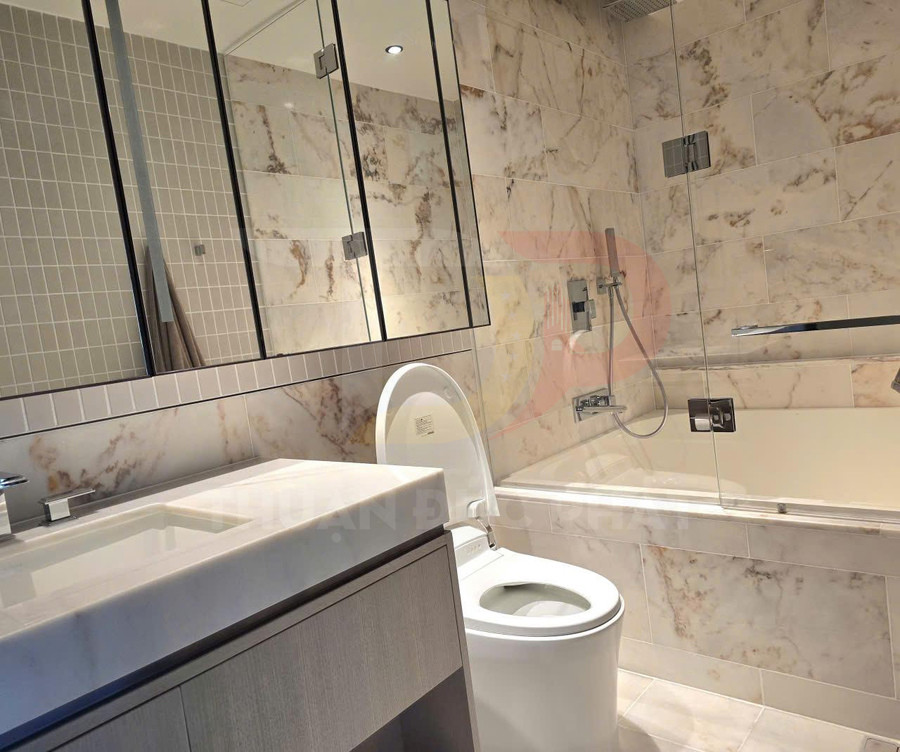 Phòng tắm hiện đại với bồn cầu, bồn tắm kính và lavabo đá hoa cương ốp tường đá marble