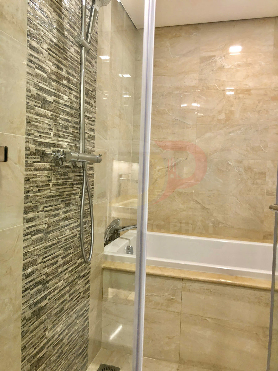 Phòng tắm kính với vòi sen đứng và bồn tắm nằm ốp gạch đá màu be hiện đại