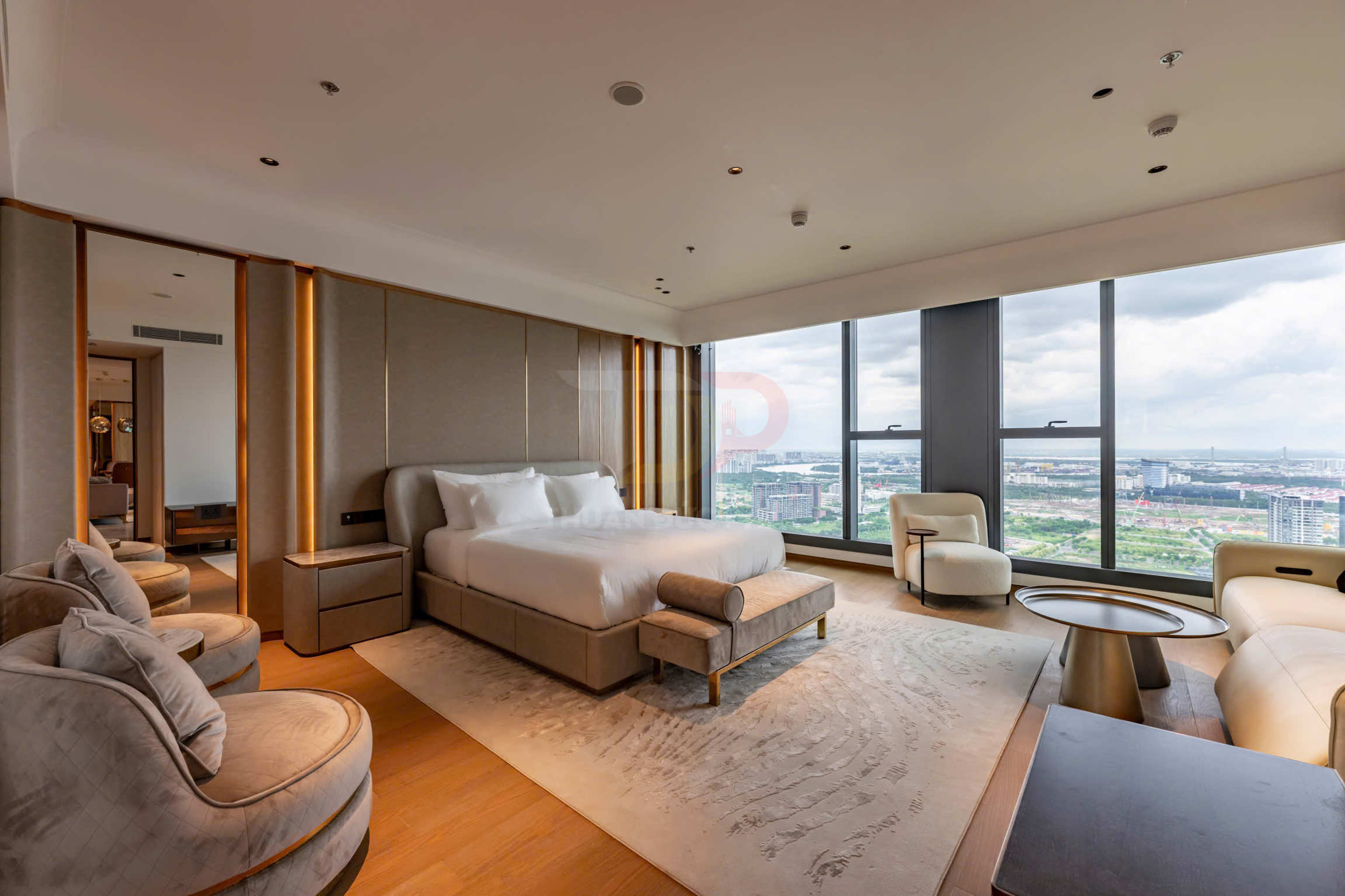 Phòng ngủ khách sạn cao cấp với giường đôi lớn, ghế sofa và cửa sổ kính toàn cảnh thành phố