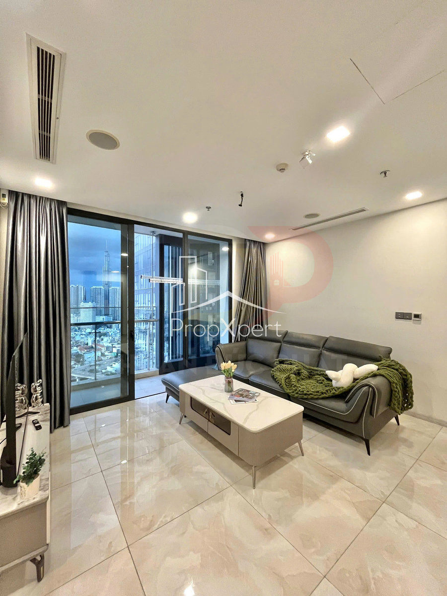 Phòng khách chung cư hiện đại với sofa da xám, bàn trà đá và cửa kính lớn nhìn ra thành phố