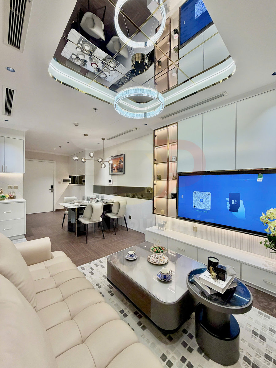 Phòng khách chung cư hiện đại với sofa kem, bàn trà đôi, kệ tivi trắng và đèn trần trang trí sang trọng