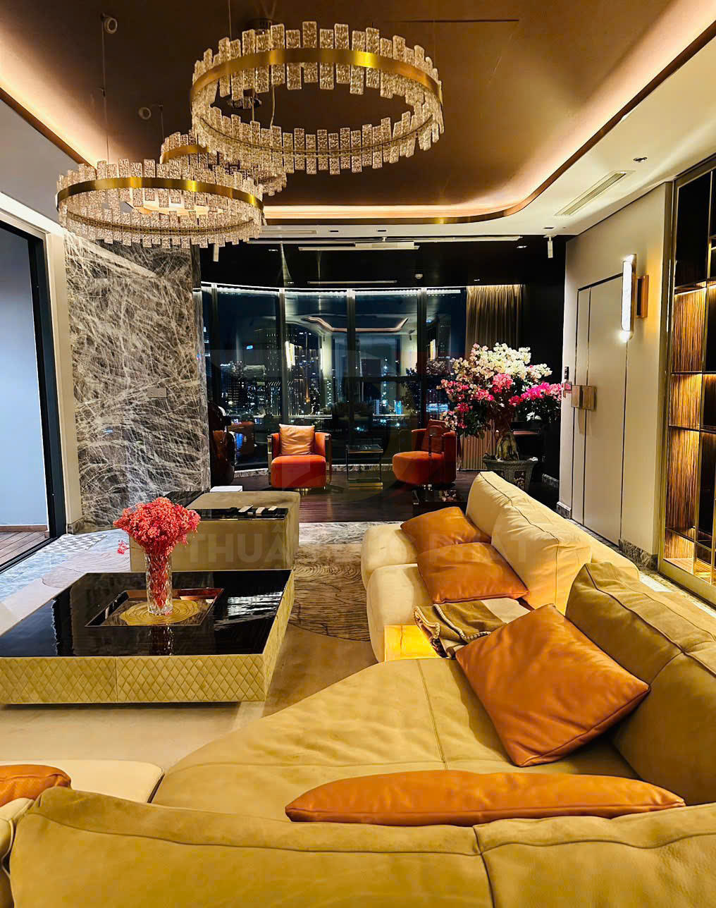 Phòng khách sang trọng với sofa da màu be cam, bàn trà đá đen và đèn chùm pha lê tròn hiện đại