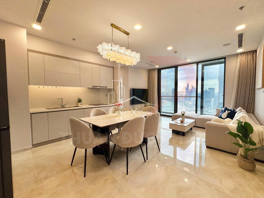 Phòng khách căn hộ cao cấp với sofa chữ L, bàn ăn và bếp liền kề, cửa kính lớn view thành phố