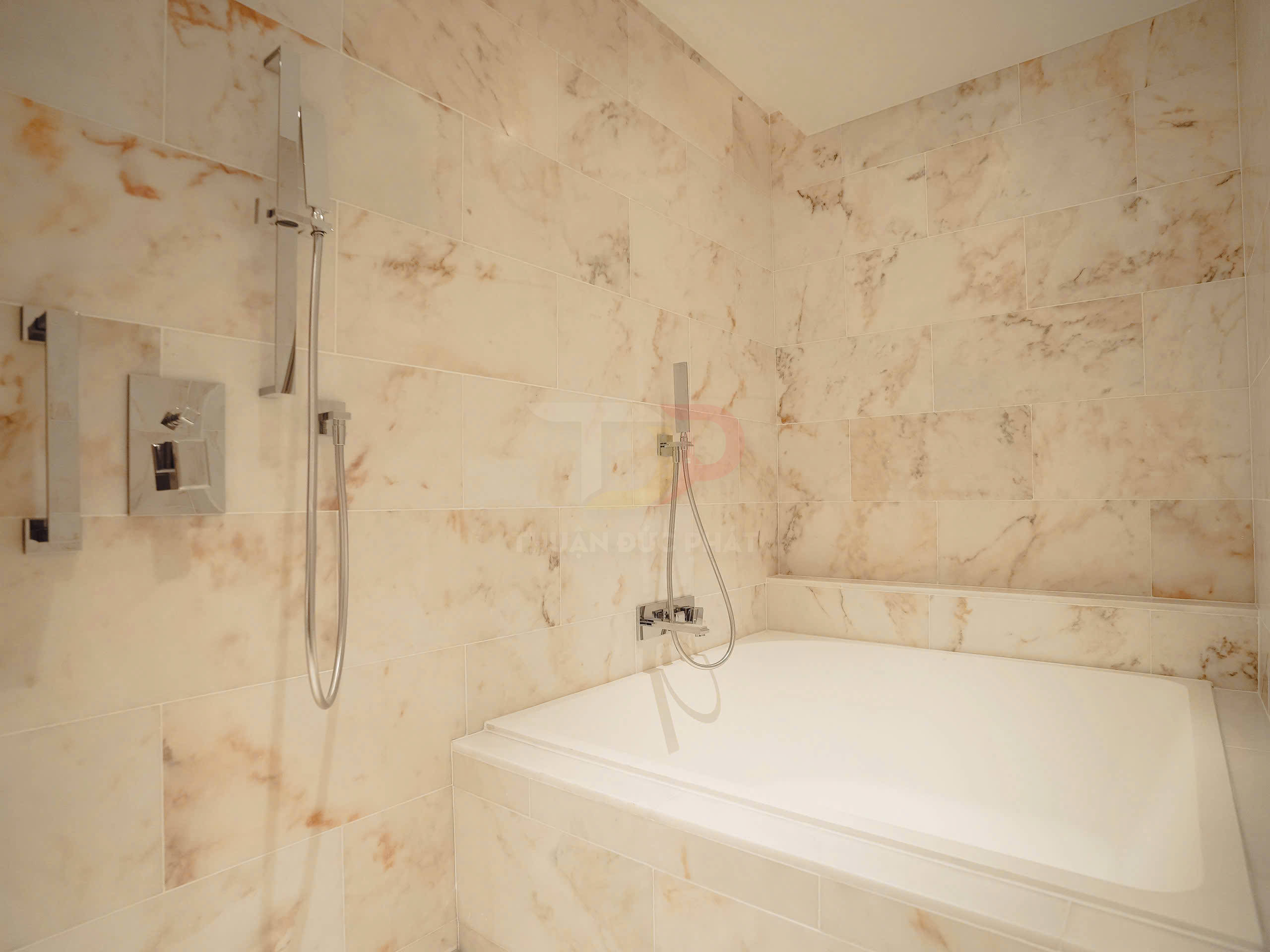 Bồn tắm nằm kèm vòi sen tay hiện đại trong phòng tắm ốp đá marble sáng màu