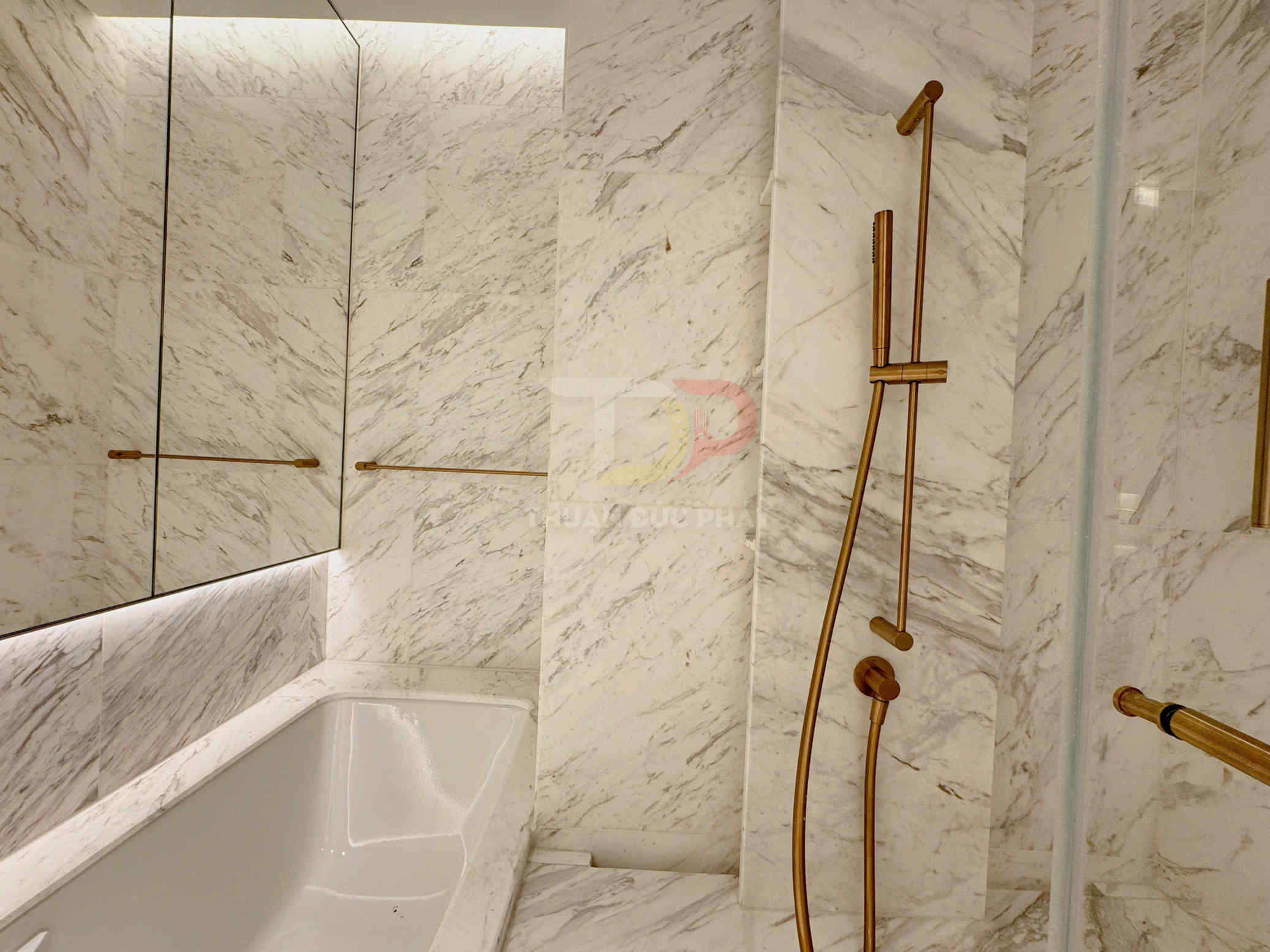 Phòng tắm đá marble với bồn tắm và bộ vòi sen màu vàng sang trọng