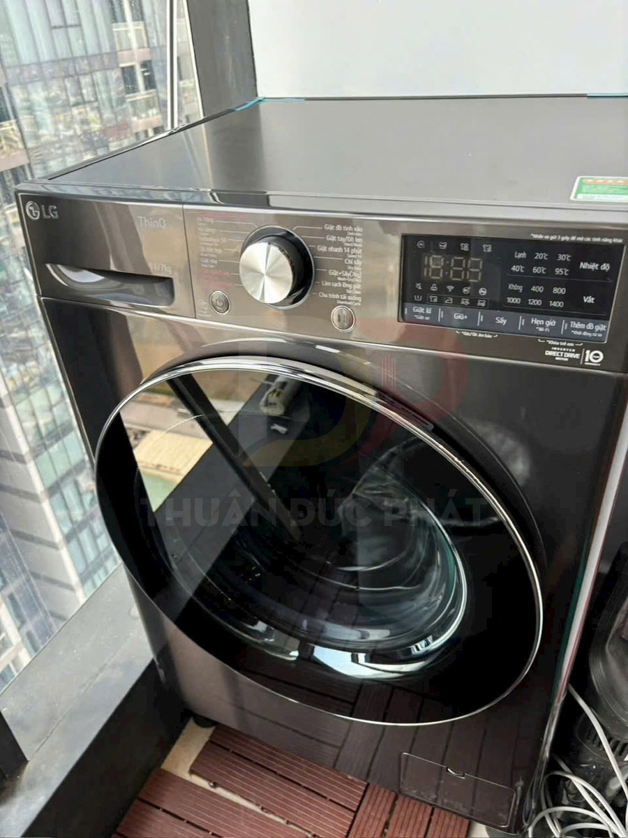 Máy giặt sấy cửa trước LG màu đen đặt cạnh cửa kính ban công