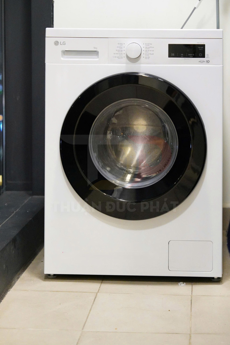 Máy giặt cửa trước LG màu trắng đặt trên nền gạch trong phòng giặt
