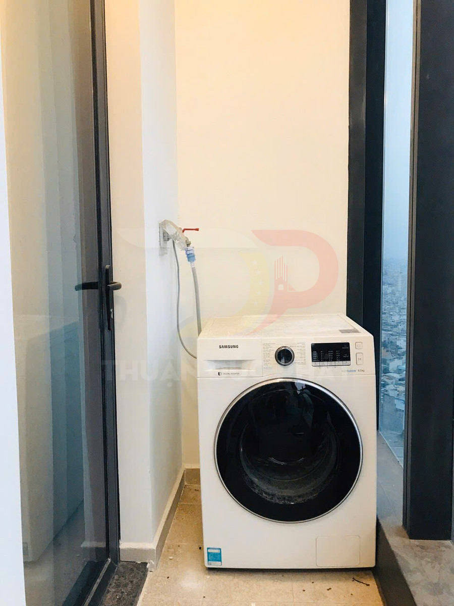 Máy giặt cửa trước Samsung màu trắng đặt cạnh cửa kính trong căn hộ
