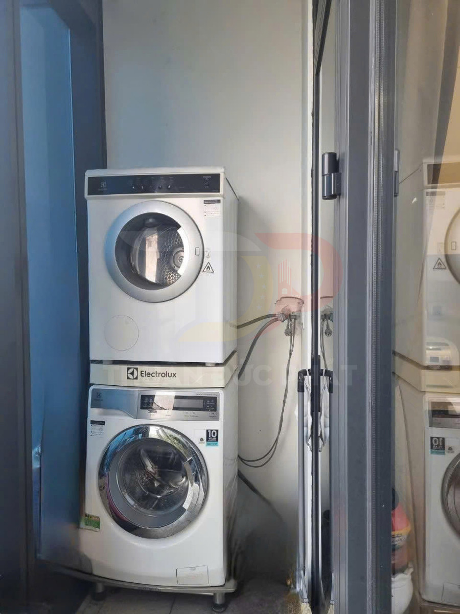Máy giặt và máy sấy Electrolux xếp chồng trong góc ban công nhỏ có vòi nước