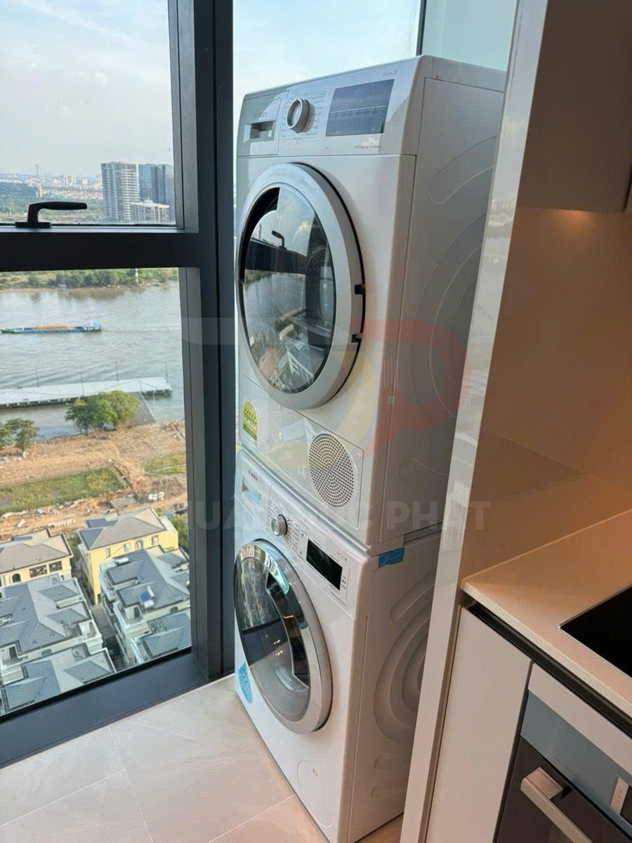Bộ máy giặt và máy sấy cửa trước xếp chồng cạnh cửa sổ trong căn hộ hiện đại