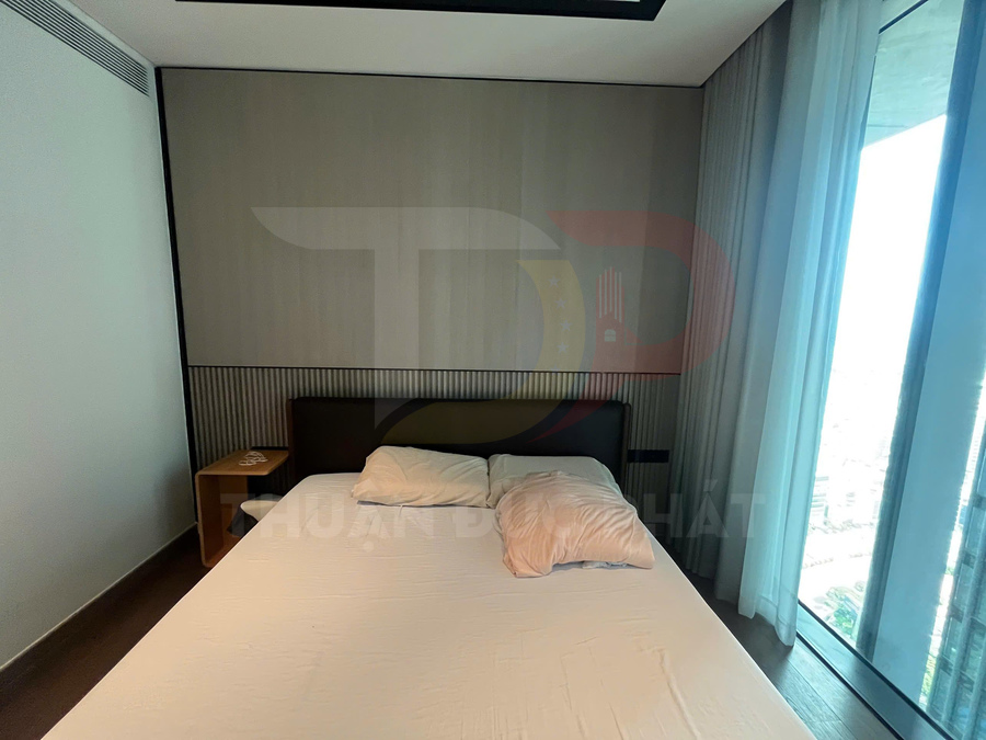 Giường ngủ hiện đại với nệm trắng, hai gối và cửa kính lớn đón ánh sáng tự nhiên