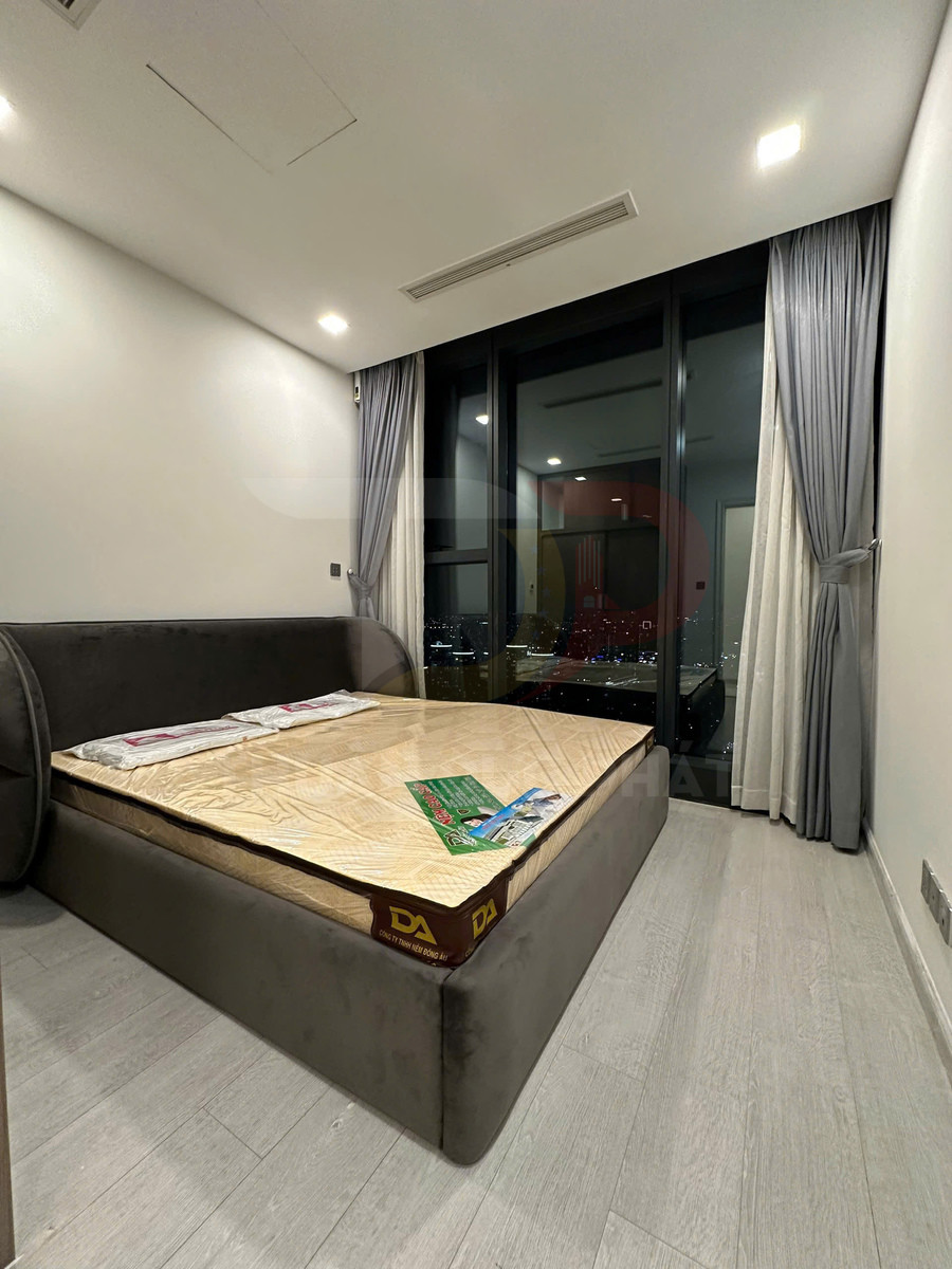 Giường ngủ bọc nệm màu xám với nệm cao su mới trong phòng ngủ hiện đại có cửa kính lớn nhìn ra ban đêm