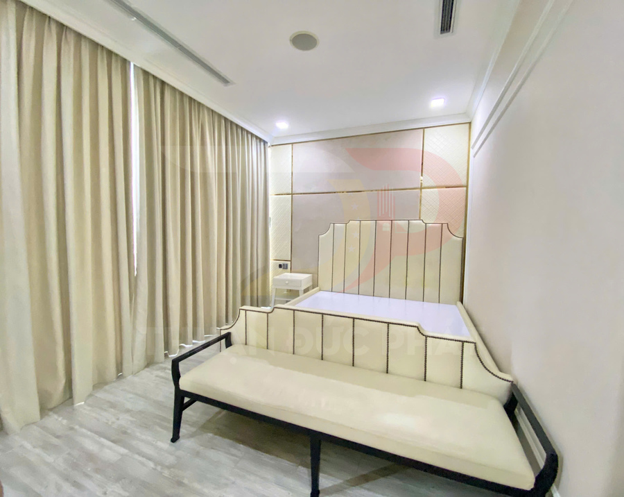 Phòng ngủ hiện đại với giường bọc da màu kem, ghế dài đồng bộ và rèm cửa cùng tông sáng
